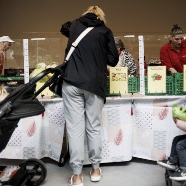 A woman at a food distribution center next to two strollers