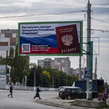 People cross a street with a billboard reading "How to get a passport of a citizen of Russia" in the occupied territory of Luhansk, September 22, 2022.