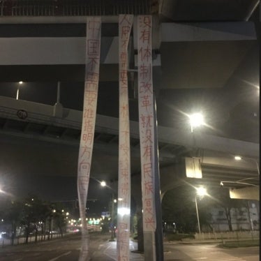 Three pro-democracy banners hang from an overpass outside the Chengdu Chadianzi Station in China’s Sichuan province on the morning of April 15, 2025.