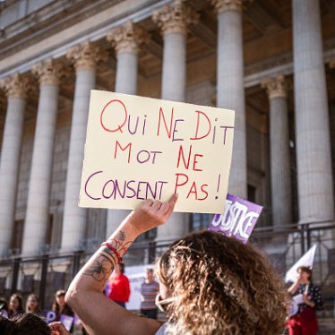 An individual holding a sign saying “Not saying anything does not equal consent”  in front of the Palais de Justice during a rally in support of all victims of gender and sexual violence in Lyon, France, October 19, 2024.