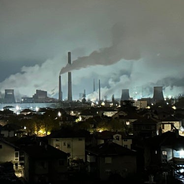 Smoke billowing from towers at a coal plant near a residential neighborhood