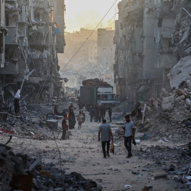 Palestinians walk through the rubble of residential buildings