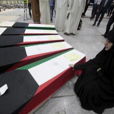 A woman grieves next to the coffins of victims of the bombing at the Imam Sadiq Mosque mosque in Kuwait City, at the international airport in Najaf, south of Baghdad, June 27, 2015.