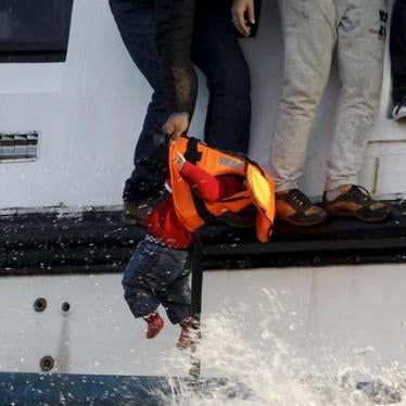 A toddler is saved from the Aegean Sea as one refugee hands the child to a volunteer lifeguard near the Greek island of Lesbos, October 30, 2015.