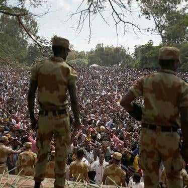 Security officials watch as demonstrators chant slogans while flashing the protest gesture during Irreecha, the thanksgiving festival of the Oromo people, in Bishoftu town, Oromia region, Ethiopia, on October 2, 2016. 