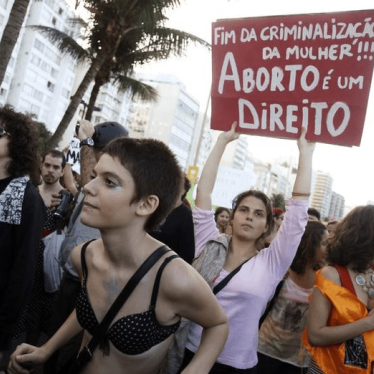 Pessoas participam da manifestação "Marcha das Vadias" na praia de Copacabana, no Rio de Janeiro, onde o Papa Francisco celebrou uma missa à noite, em julho de 2013. No cartaz está escrito "Fim da criminalização da mulher. Aborto é um direito"