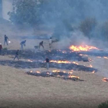Conforme caen las llamas de los cohetes incendiarios, nubes de humo cubren las tierras de cultivo en el oeste de Idlib, Siria, el 30 de julio de 2018.