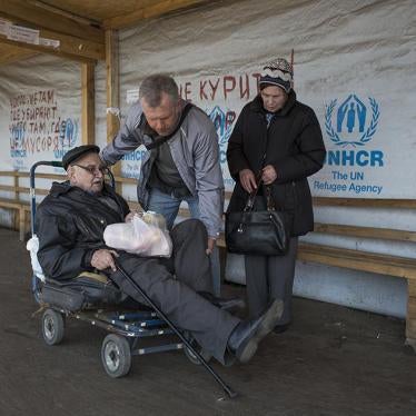 An older man with a disability sits on an old luggage cart preparing to cross the Stanitsa Luhanska border point in Eastern Ukraine. 