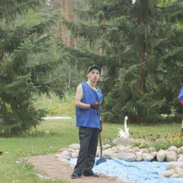 A young man does yard work on the grounds of a closed state institution for adults with disabilities.