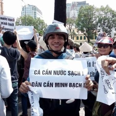 Nguyen Ngoc Anh at an anti-Formosa protest in 2016. The signs he is holding say: Fish Need Clean Water, People Need Transparency.  