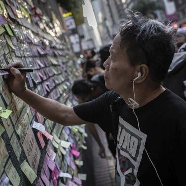 A man glues a sticker label with messages against the extradition bill and pro-democracy in a Lennon wall in Wan Chai, Hong Kong