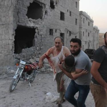 Residents rescue injured child after strike on the displacement center in Hass on August 16, 2019.