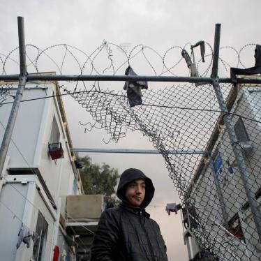 A boy stands next to a hole in the fence of the Moria camp following rainfall, on the island of Lesbos, Greece, November 22, 2019. REUTERS/Elias Marcou