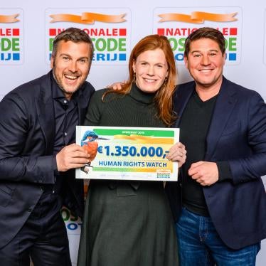 Two men and a woman holding a sign and smiling