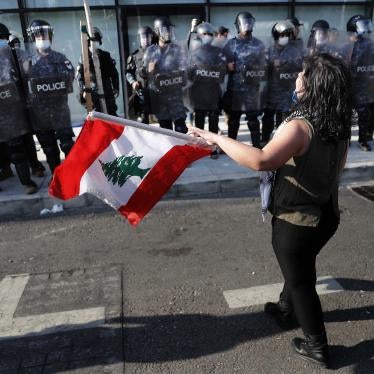 An anti-government protester holds a Lebanese flag in front the riot police during a protest against the deepening financial crisis, in Beirut, Lebanon, Tuesday, April 28, 2020.