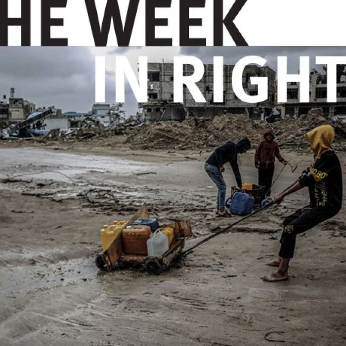 Figures drag belongings across road. 