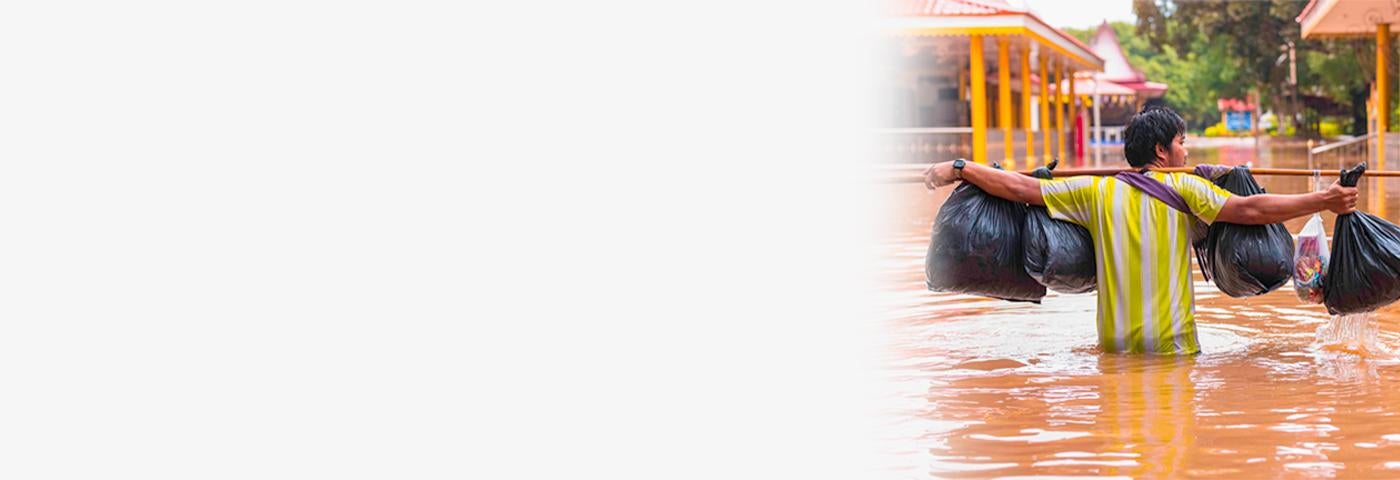 A man walks on a submerged road after a flash flood in Lopburi, Thailand, September 27, 2021. © 2021 Phobthum Yingpaiboonsuk/SOPA I/Sipa via AP Images